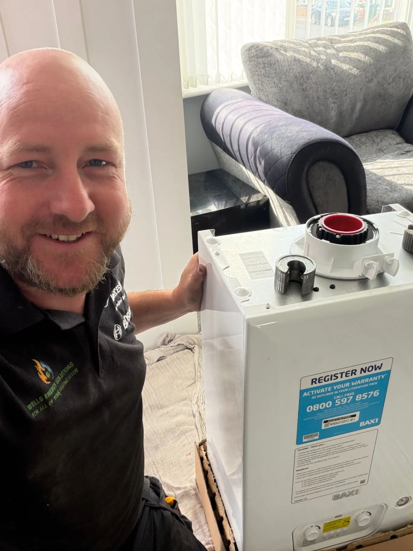 Wells Energy Solutions engineer smiling beside a boiler during a home visit