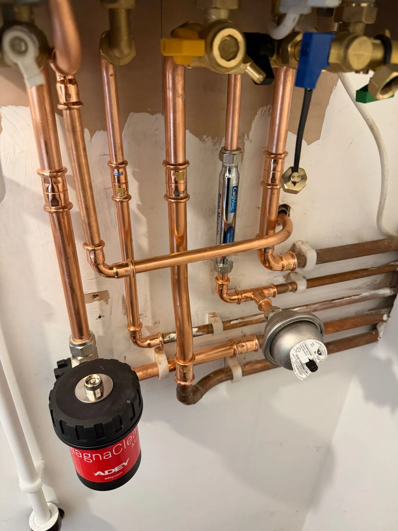 Close view of copper boiler pipework, valves and a magnetic filter